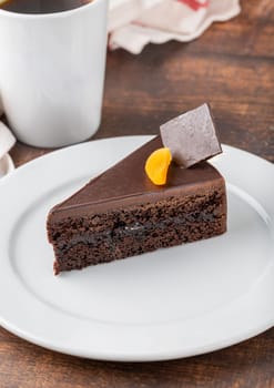 Orange and chocolate cake with cup of coffee on wooden table