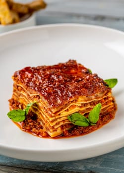 Bechamel sauce and minced meat lasagna on wooden table