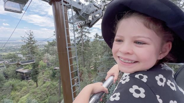 Little girl taking a ride on the ski lift at the Cheyenne Mountain Zoo on summer school break.