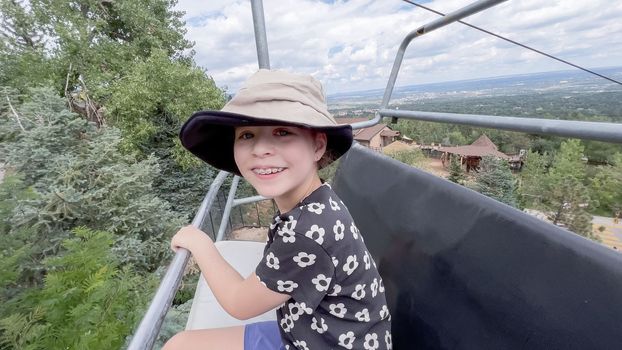 Little girl taking a ride on the ski lift at the Cheyenne Mountain Zoo on summer school break.
