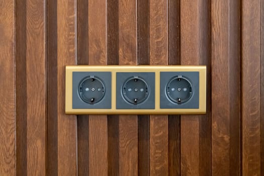 Modern triple socket mounted on wood veneer wall