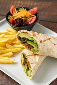 Vegetarian wrap french fries with vegetables on a white porcelain plate