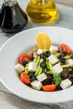 Mediterranean salad with olives and cheese on a white porcelain plate