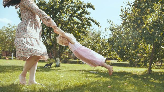 A mother circles her daughter in the garden outside the house