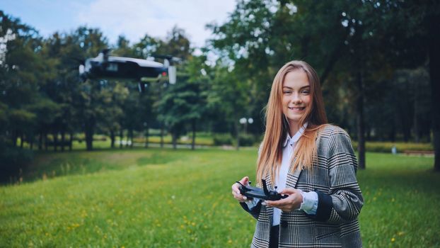 A cute girl controls a drone in the park