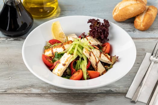 Salad with tomato and halloumi cheese on wooden table