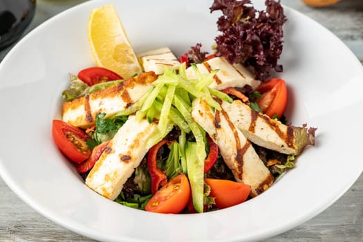 Salad with tomato and halloumi cheese on wooden table