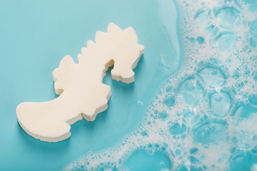 White soap in the shape of a seahorse with foam on a blue background