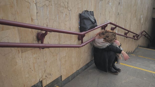 A young girl crying by the stairs in the subway