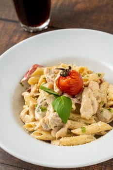 Penne arrabiata pasta with chicken on a white porcelain plate