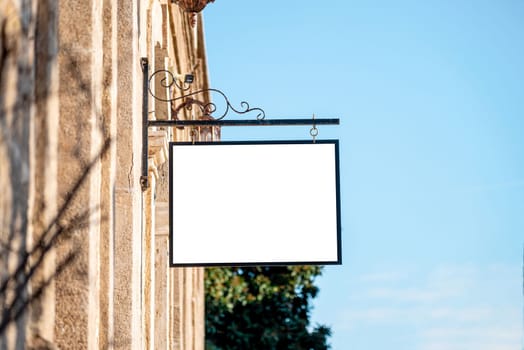 Blank signboard mockup hanging on the wall of the store in the street