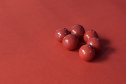 A delicious red chocolate on a red background.