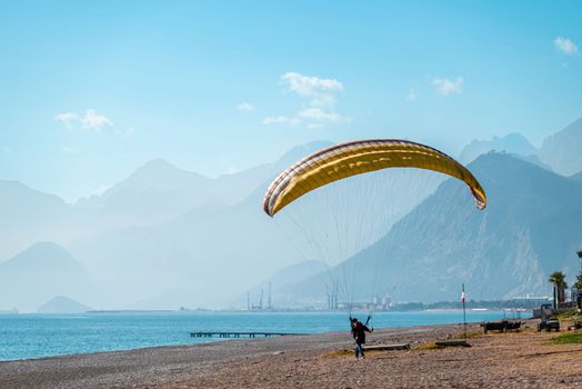 Man practicing paragliding on a windy day on the beach by the sea