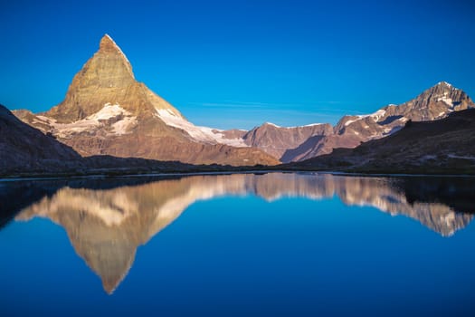 Reflection of the Matterhorn on blue and placid lake at sunrise, Swiss Alps, Zermatt, Switzerland