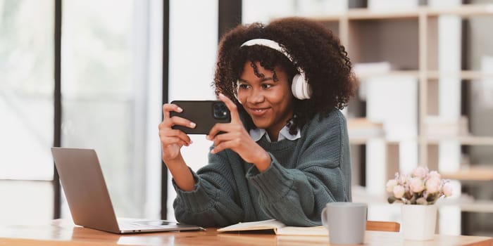 Excited Young black African woman wear headphone and enjoy with game via app on mobile phone