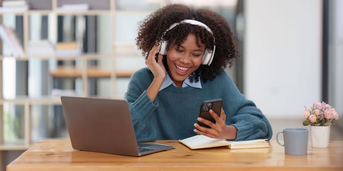 Young black African woman wear headphone and enjoy with music via music app on mobile phone