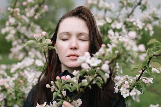 Beautiful young woman near blooming spring tree. Youth, love, fashion, romantic and lifestyle concept