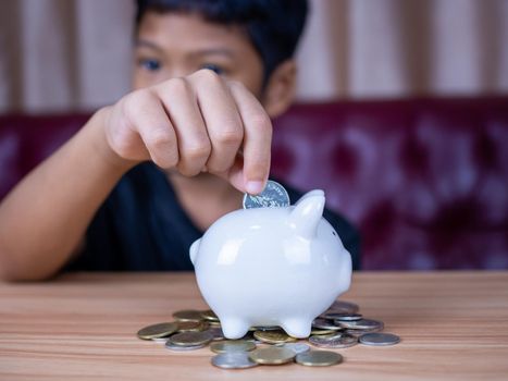 Boy saving money in a white pig piggy bank.Saving concept. Saving for the future.