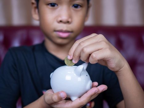 Boy saving money in a white pig piggy bank.Saving concept. Saving for the future.