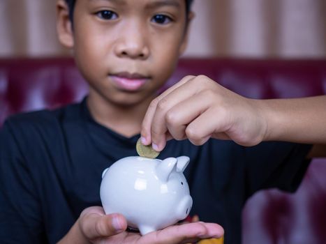 Boy saving money in a white pig piggy bank.Saving concept. Saving for the future.