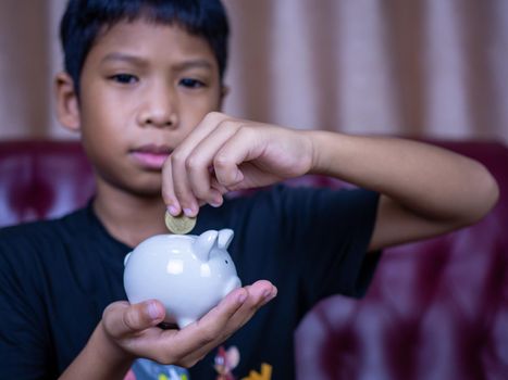 Boy saving money in a white pig piggy bank.Saving concept. Saving for the future.