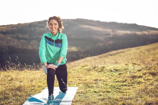 Young fitness woman doing stretching exercise after jogging in the nature.