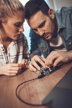 Two young colleagues technician focused on the repair of electronic equipment.