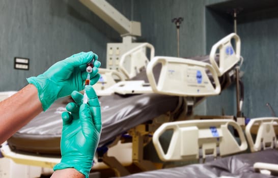 Hands of the doctors with green gloves filling a syringe