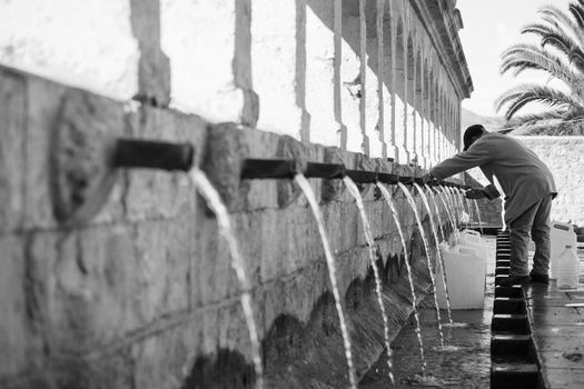 LEONFORTE, ITALY - JANUARY, 08: Man filling cans with fountain water on January 08, 2015