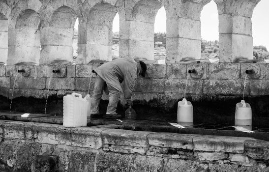 LEONFORTE, ITALY - JANUARY, 08: Man filling cans with fountain water on January 08, 2015