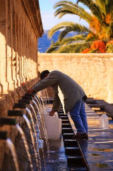 LEONFORTE, ITALY - JANUARY, 08: Man filling cans with fountain water on January 08, 2015