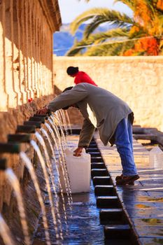 LEONFORTE, ITALY - JANUARY, 08: Man filling cans with fountain water on January 08, 2015