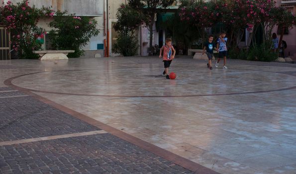 LAMPEDUSA, ITALY - AUGUST, 03: Children play soccer in the Lampedusa square on August 03, 2018
