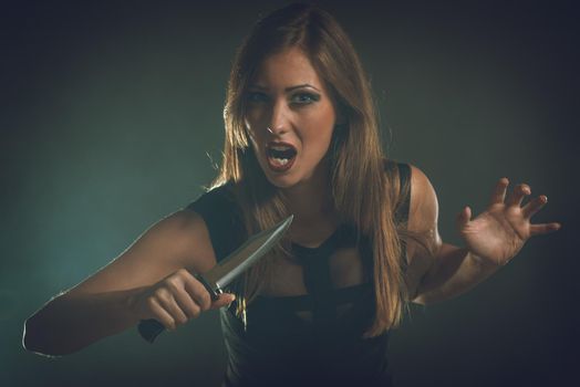 Beautiful dangerous girl with knife want to revenge for violence she experience. Looking at camera.