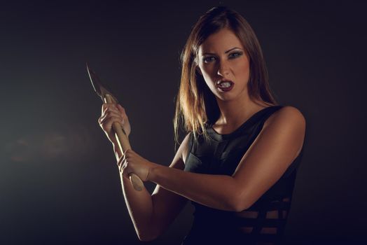 Beautiful dangerous girl with rusty axe want to revenge for violence she experience. Looking at camera.
