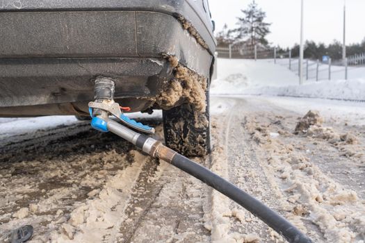 Filling the car from the bottom of the bumper with gas in the winter at the gas station.