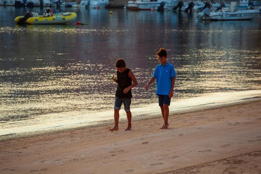 LAMPEDUSA, ITALY - AUGUST, 01: Two little boys play in the shoreline of Lampedusa at sunset on August 01, 2018