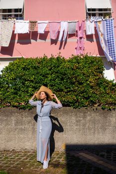 A girl in a dress and hat walks in the afternoon in an Italian town in Tuscany.