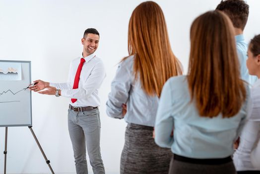 Businesspeople having meeting in a office. Young businessman standing in front of flip chart and having presentation.