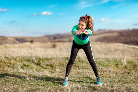 Young fitness woman doing stretching exercise after jogging in the nature.