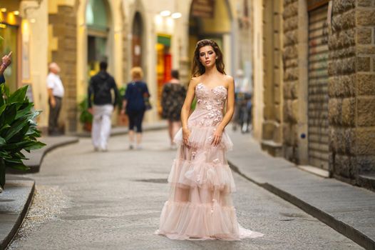 A bride in a pink wedding dress walks in Florence, Italy.