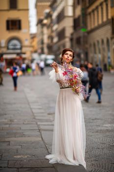 a bride in a wedding dress with a Venetian mask in her hands in Florence.Italy.