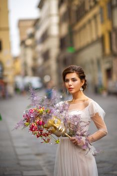 a bride in a wedding dress with a Venetian mask in her hands in Florence.Italy.