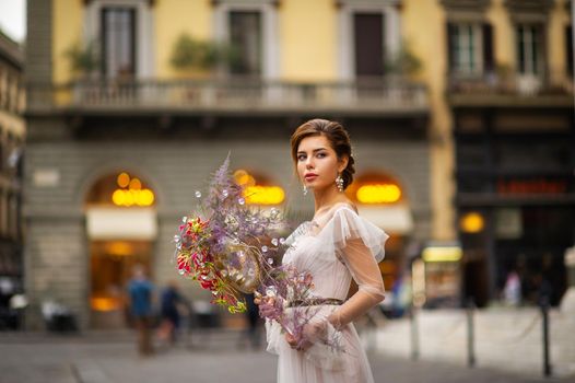 a bride in a wedding dress with a Venetian mask in her hands in Florence.Italy.