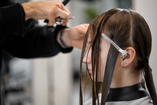 male hairdresser is combing the hair of the female client. hairdresser doing hair to his client woman