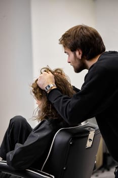Beautiful young woman in modern hair salon. hairdresser checking hairstyle of caucasian girl
