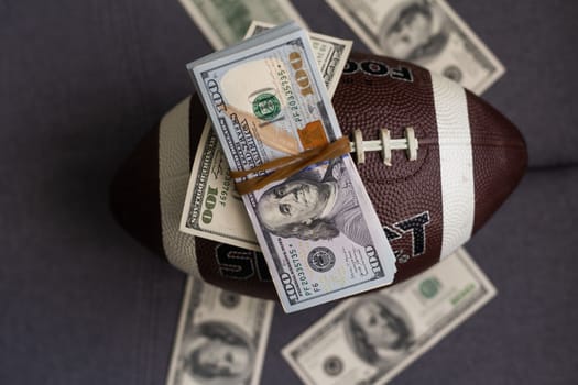 Football ball and money on gray background.