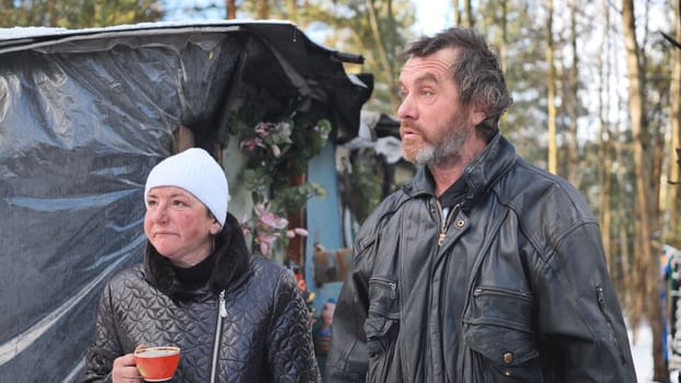 A homeless man and woman giving an interview in the winter in the woods