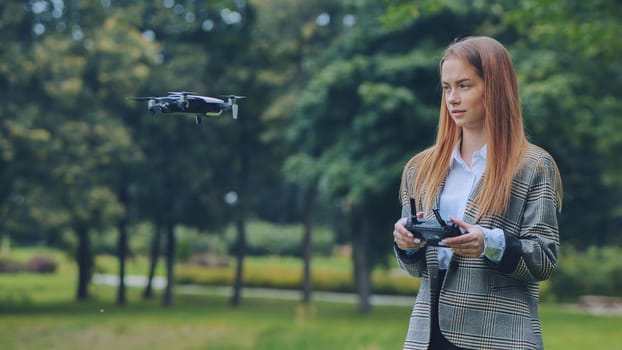 A cute girl controls a drone in the park