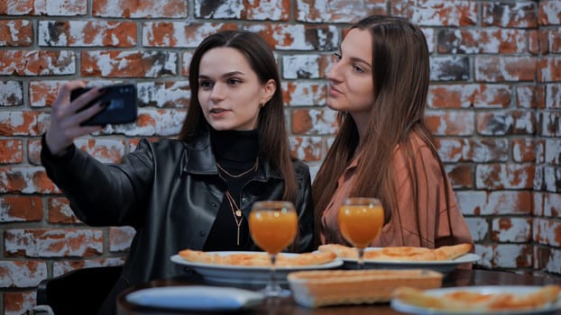 Two girls are sitting in a cafe and taking a selfie on the phone